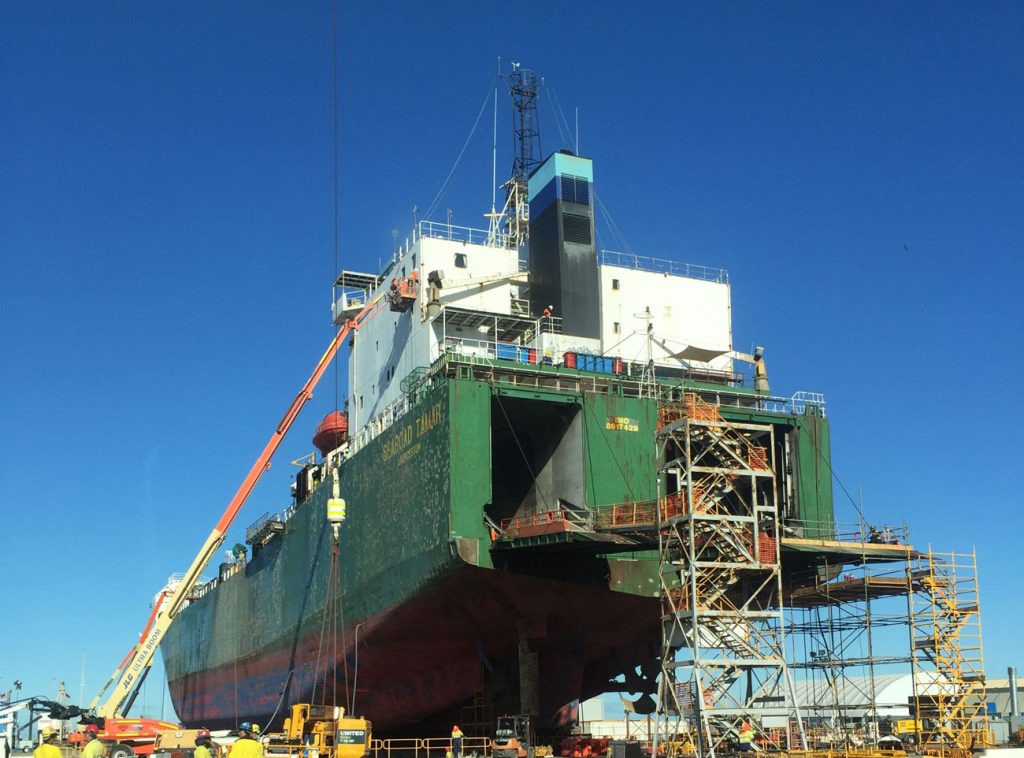 Large vessel docked, surrounded by scaffolding as a crane extends up the side. Major works being carried out by a team of WATMAR engineers during a programmed sustainment contract